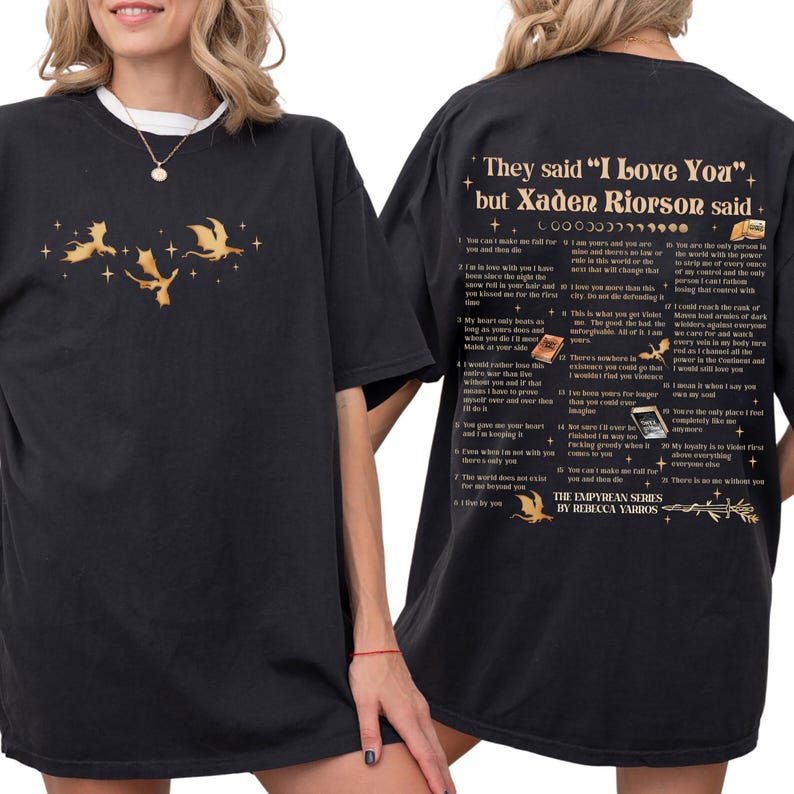 May include: Black t-shirt with a white collar featuring a gold dragon graphic and text. The back of the shirt has text that reads "They said 'I Love You' but Xaden Riorson said." and a list of quotes. The shirt is part of "The Empyrean Series" by Rebecca Yarros.