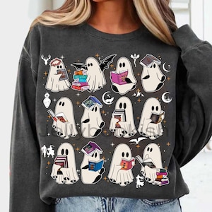 May include: Dark grey sweatshirt with a playful design of cartoon ghosts reading books. The ghosts are white with black eyes, and the books have colourful covers. The design includes stars, moons, and other Halloween-themed elements.