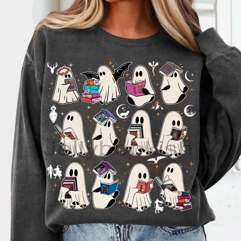 May include: Dark grey sweatshirt with a playful design of cartoon ghosts reading books. The ghosts are white with black eyes, and the books have colourful covers. The design includes stars, moons, and other Halloween-themed elements.