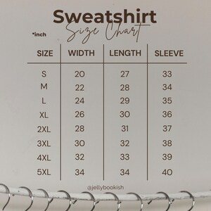 May include: A size chart for sweatshirts, with measurements in inches. The chart includes sizes S through 5XL, detailing width, length, and sleeve measurements. The text "Sweatshirt Size Chart" is at the top, with the brand's Instagram handle, @jellybookish, at the bottom.
