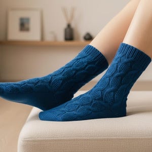 May include: A pair of blue cable knit socks. The socks are a solid, deep blue color and feature a textured cable knit pattern. The socks are worn on a person's feet, resting on a neutral-colored surface.