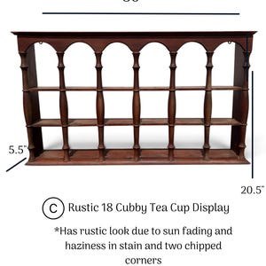 May include: A brown wooden display shelf with 18 cubbies, featuring arched top openings and spindle-style vertical supports. The unit measures 36 inches wide, 20.5 inches high, and 5.5 inches deep, showing sun fading, stain haziness, and two chipped corners.