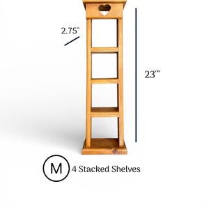 May include: A light brown wooden tower with four stacked shelves. The top section features a cutout heart shape. Dimensions are 7 inches wide, 2.75 inches deep, and 23 inches tall. The text M 4 Stacked Shelves is visible below the unit.