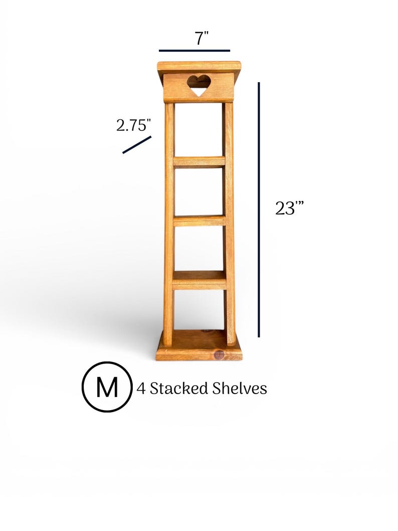 May include: A light brown wooden tower with four stacked shelves. The top section features a cutout heart shape. Dimensions are 7 inches wide, 2.75 inches deep, and 23 inches tall. The text M 4 Stacked Shelves is visible below the unit.