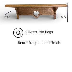 May include: A brown wooden wall shelf with a heart-shaped cutout in the center support. The shelf measures 18 inches wide, 6.5 inches deep, and 5.5 inches high. Text on the image reads: Q 1 Heart, No Pegs, Beautiful, polished finish.