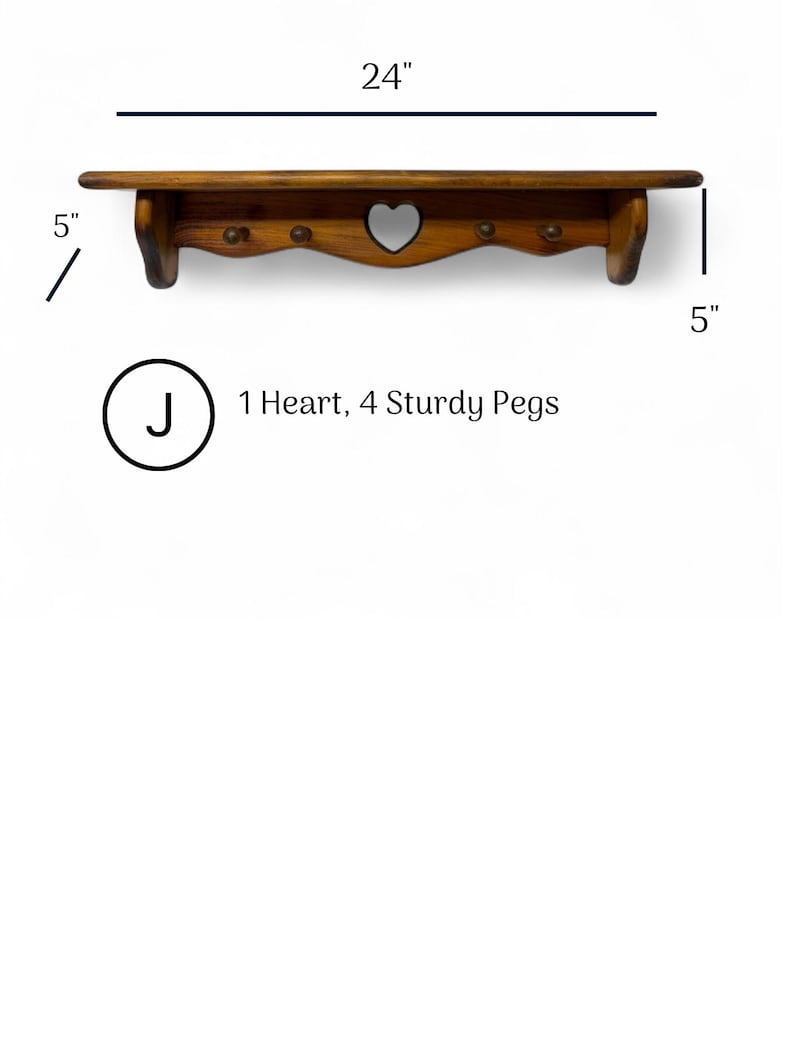 May include: A brown wooden wall shelf featuring a heart-shaped cutout in the center and four sturdy pegs. The shelf measures 24 inches in width and 5 inches in height. Text on the image reads: J 1 Heart, 4 Sturdy Pegs.