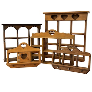 May include: A collection of five wooden wall shelves in various brown tones. Each shelf features heart-shaped cutouts, open storage compartments, and some include small doors or hooks. The shelves vary in size and structural design, showcasing natural wood grain textures and smooth finishes throughout the set.