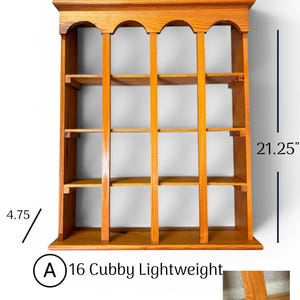 May include: A light brown wooden wall shelf with 16 cubbies, featuring an arched top design. It measures 17.5 inches wide, 21.25 inches high, and 4.75 inches deep. A small crack is visible on the bottom right vertical post of the unit.