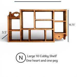 May include: A brown wooden wall shelf with ten cubbies, a heart-shaped cutout on the top left, and a single peg on the bottom right. The shelf measures 30 inches wide, 16.75 inches high, and 3.5 inches deep. Text reads: Large 10 Cubby Shelf, One heart and one peg.