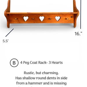 May include: A wooden coat rack with four pegs and three heart-shaped cutouts. The rack measures 37.5 inches wide, 16 inches high, and 5.5 inches deep. It features visible hammer dents on the side and lacks wood screw covers on the side.