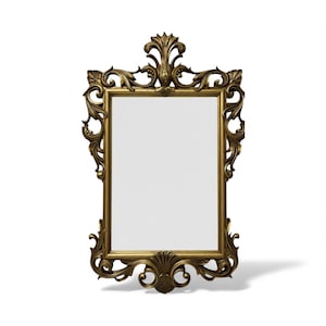 May include: A rectangular gold-colored mirror with an ornate, detailed frame. The frame features scrolling leaf and floral designs, with a decorative crest at the top and a shell-like motif at the bottom. The mirror's surface is clear and reflective.