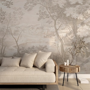 May include: A neutral-toned living room scene featuring a beige sofa with three pillows, a small wooden side table, and a landscape mural. The mural depicts a sepia-toned countryside scene with trees and buildings.