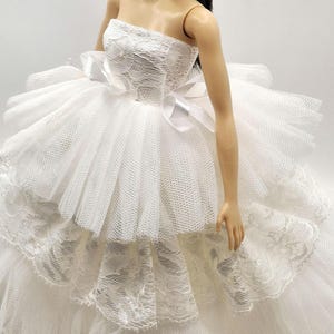 May include: A white strapless dress with a lace bodice and tulle skirt. The skirt has multiple layers and is very full. The dress is perfect for a special occasion.
