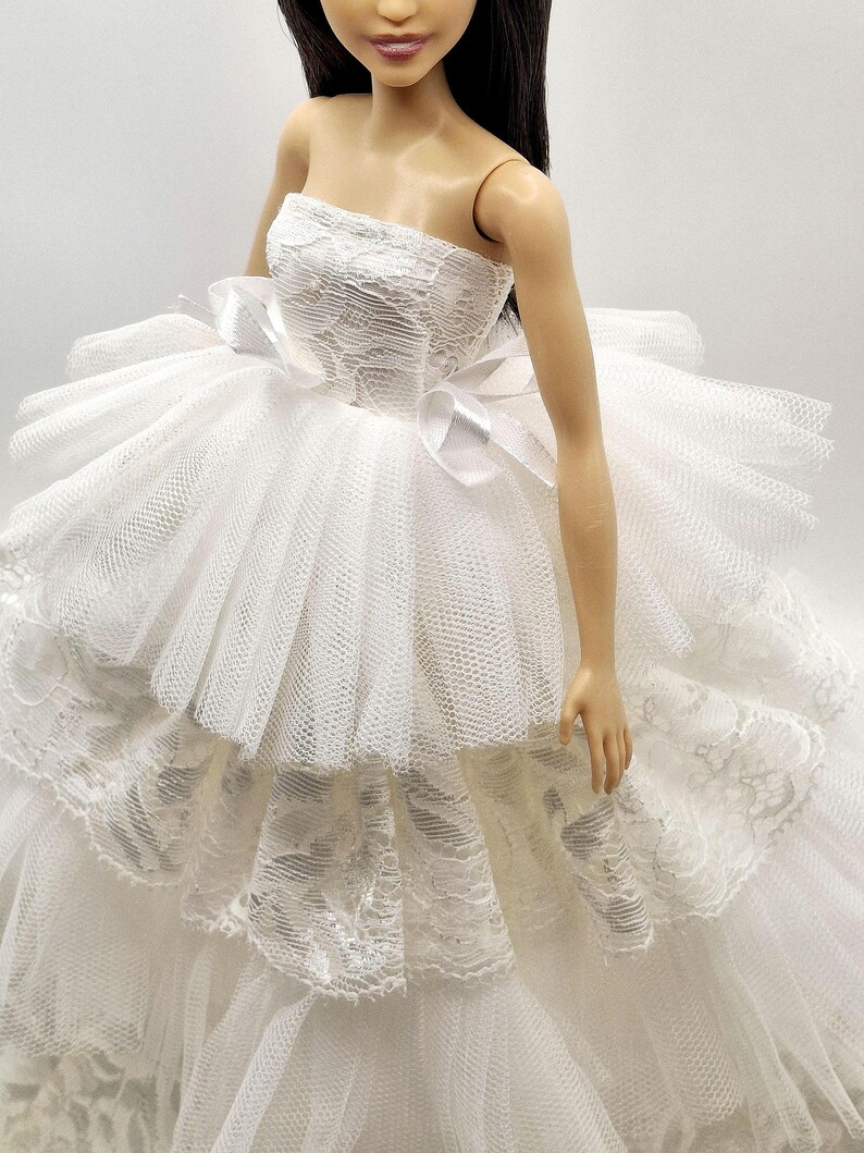 May include: A white strapless dress with a lace bodice and tulle skirt. The skirt has multiple layers and is very full. The dress is perfect for a special occasion.