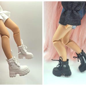 May include: A pair of doll legs wearing white platform lace-up boots with side buckles and a second pair of doll legs wearing black platform lace-up boots with side buckles, both featuring thick lug soles and white laces.