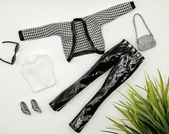 May include: A black and white houndstooth jacket, a white ribbed turtleneck sweater, black patent leather pants with a decorative belt, silver high heels, black sunglasses, and a small silver handbag arranged on a flat surface.