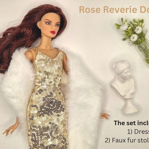 May include: A doll wearing a gold sequined dress and a white faux fur stole. The image includes a small white bust, a vase of flowers, and the text "Rose Reverie Dolls". The set includes a dress and a faux fur stole/shawl.