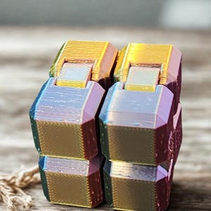 May include: A multi-colored fidget cube toy with a gold finish. The cube is made of multiple smaller cubes that can be rotated and flipped.
