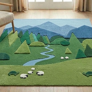 以下が含まれることがあります： 風景デザインの、気まぐれな長方形のラグ。緑の牧草地、曲がりくねった青い川、緑の木々、青い山々が描かれています。羊とカメが牧草地に散らばっています。