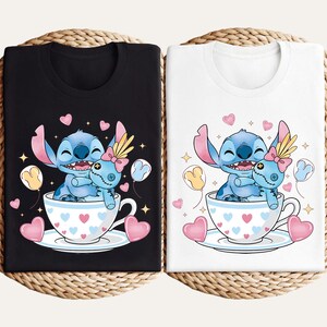 Puede incluir: Camisetas negras y blancas con un dise&ntilde;o de personaje de dibujos animados y mu&ntilde;eca en una taza de t&eacute;. Las tazas de t&eacute; tienen patrones de corazones, y el dise&ntilde;o incluye corazones y estrellas. Las camisetas se muestran sobre una superficie tejida.