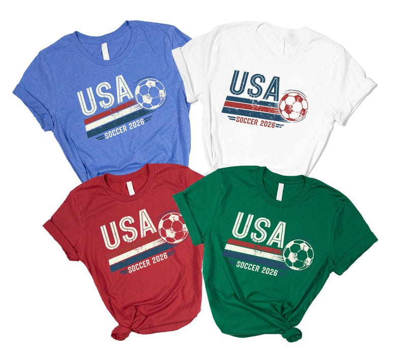 May include: Four short-sleeve t-shirts in blue, white, red, and green. Each shirt features a graphic with the text USA and SOCCER 2026, accompanied by a soccer ball illustration and horizontal stripes in a distressed, vintage-inspired print style.