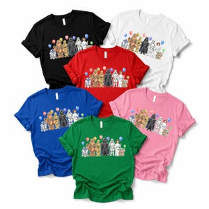 May include: A collection of short-sleeved t-shirts in various colors, including black, red, white, blue, green, and pink. Each shirt features a colorful graphic of Star Wars characters with balloons, suitable for fans of the franchise.