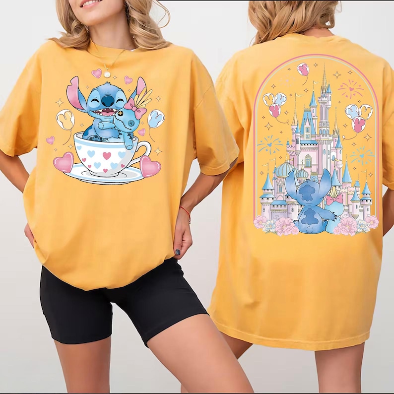 Puede incluir: Camiseta amarilla mostaza con un dise&ntilde;o de dibujos animados de Stitch. La parte delantera muestra a Stitch en una taza de t&eacute; con corazones y globos. La parte trasera muestra a Stitch con un castillo y fuegos artificiales. Una camiseta divertida e informal.