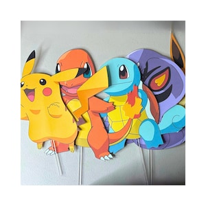 May include: A collection of colorful, cartoon character cutouts, including Pikachu, Charmander, Squirtle, and a purple character. Each cutout is mounted on a clear stick, suggesting they are photo booth props or party decorations. The characters are brightly colored.