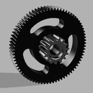 May include: A black gear with a toothed outer rim and three curved cutouts. Inside, a smaller gear is visible. The gears are set against a gray background, suggesting a mechanical or engineering theme.