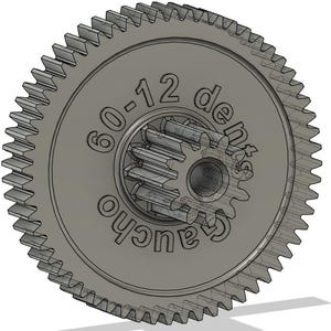 May include: A gray gear with a toothed outer ring and a smaller gear in the center. The text "60-12 dents gaucho" is inscribed on the gear's surface. The gear is designed for mechanical applications.