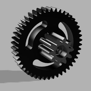 May include: A black gear with a smaller gear nested inside. The larger gear has three curved cutouts and many teeth around the outer edge. The smaller gear has a series of teeth around its circumference.