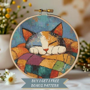 May include: A cross-stitch embroidery of a sleeping cat with orange, white, and black fur, resting on a colorful patchwork quilt. The embroidery is set in a wooden hoop. The text "BUY 1 GET 1 FREE BONUS PATTERN" is displayed on a banner below the hoop.