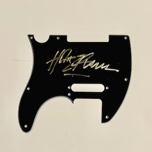May include: Black guitar pickguard with a gold signature that reads "Hot Tuna".