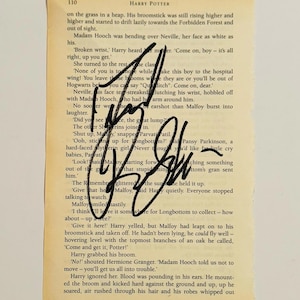 Puede incluir: Una página de un libro de Harry Potter con texto y una firma. La página tiene un aspecto envejecido. La firma, en tinta negra, cubre parte del texto. El texto es legible.