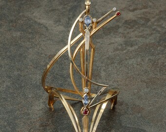 14 karat white and yellow gold wearable "Celebration" sculpture with sapphires, rubies and diamonds.