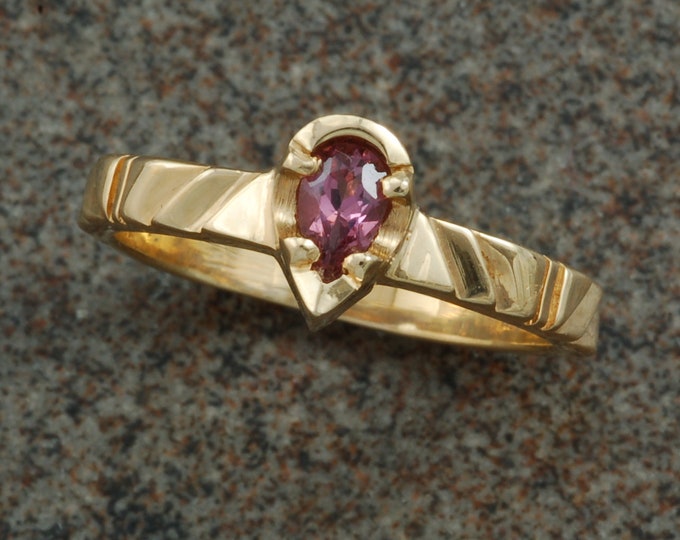 Carved gold ring set with pear shaped natural pink sapphire.