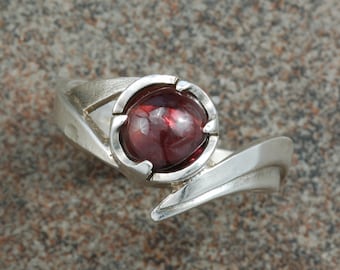 Garnet cabochon set in asymmetrical sterling silver ring.