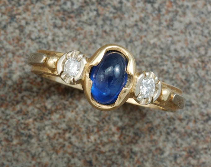 Yellow and white gold sapphire cabochon ring with side set diamonds.