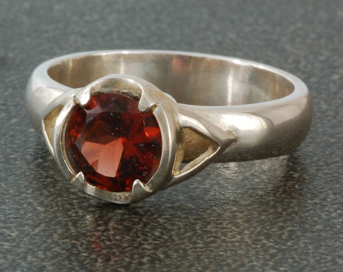 Sterling silver ring set with round garnet.