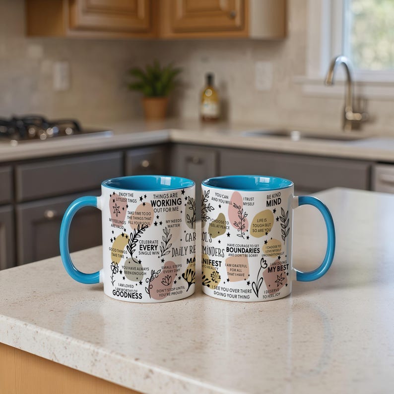 May include: Two white ceramic mugs with blue handles and rims. The mugs are decorated with inspirational phrases, floral designs, and colorful shapes. The text includes phrases like "Things are working out for me" and "Celebrate every single win."