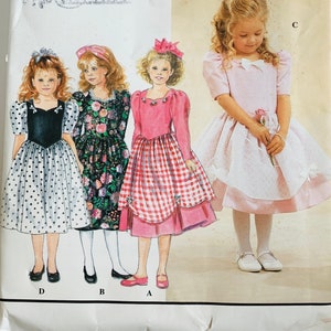 May include: Simplicity sewing pattern 0608 featuring four little girl's dress designs. The dresses include a polka dot dress, a floral dress, a red gingham dress, and a pink dress with a bow.