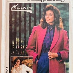 May include: Simplicity Connoisseur Collection sewing pattern. The image features a woman wearing a pink coat, blue pants, and a plaid shirt. The pattern includes a large size option. The overall aesthetic is vintage.