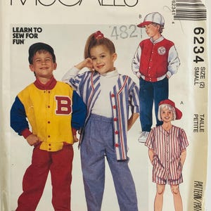 May include: McCall's sewing pattern featuring children's baseball-themed outfits. The pattern includes a yellow and blue jacket with a red "B", a striped jacket and pants, and a striped shirt and shorts set. The text "LEARN TO SEW FOR FUN" is visible.
