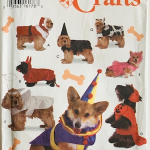 May include: Simplicity Crafts dog costume pattern. The pattern features various dog costumes, including a Santa, devil, witch, clown, and angel. The costumes are shown on different dog breeds. The pattern includes the text "ONE SIZE".