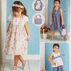 May include: Simplicity sewing pattern S9559 for girls' clothing, including a dress, top, and pants. The pattern features a floral dress, a blue dress, and a white top with blue pants. The image also shows a tote bag with a bunny design.