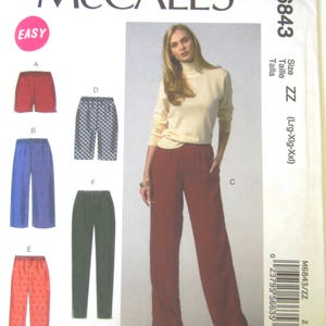 May include: McCall's sewing pattern M6843 featuring various styles of pants. The pattern includes options for shorts, wide-leg pants, and other designs. The cover shows a woman wearing a cream-colored turtleneck and burgundy pants.