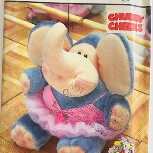 May include: A Simplicity crafts pattern featuring a blue stuffed elephant wearing a pink tutu and a pink rose. The pattern is labeled "Chubby Cheeks" and includes the text "Cunningham Fabrics, Vicksburg, Michigan, Phone: 649-3701".