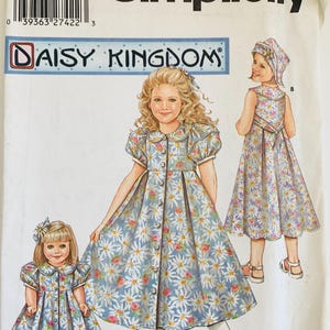 May include: Simplicity sewing pattern 5203 for Daisy Kingdom, size HH 3, 4, 5, 6. The envelope features illustrations of a dress with a blue background, white daisy print, pink floral accents, a Peter Pan collar, and puff sleeves, shown on a child and a doll.