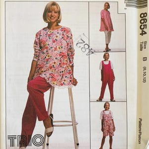 May include: A vintage sewing pattern featuring a woman modeling three different outfits. The main image shows a floral tunic with pink pants. Additional images display a pink top with white pants, pink overalls, and a floral romper. The pattern number is 8654.