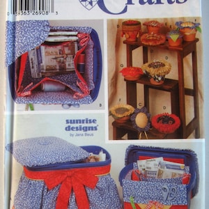May include: Simplicity Crafts sewing pattern featuring various craft organizers and pincushions. The organizers are blue with a white floral pattern and red accents. The pincushions are in small terracotta pots.